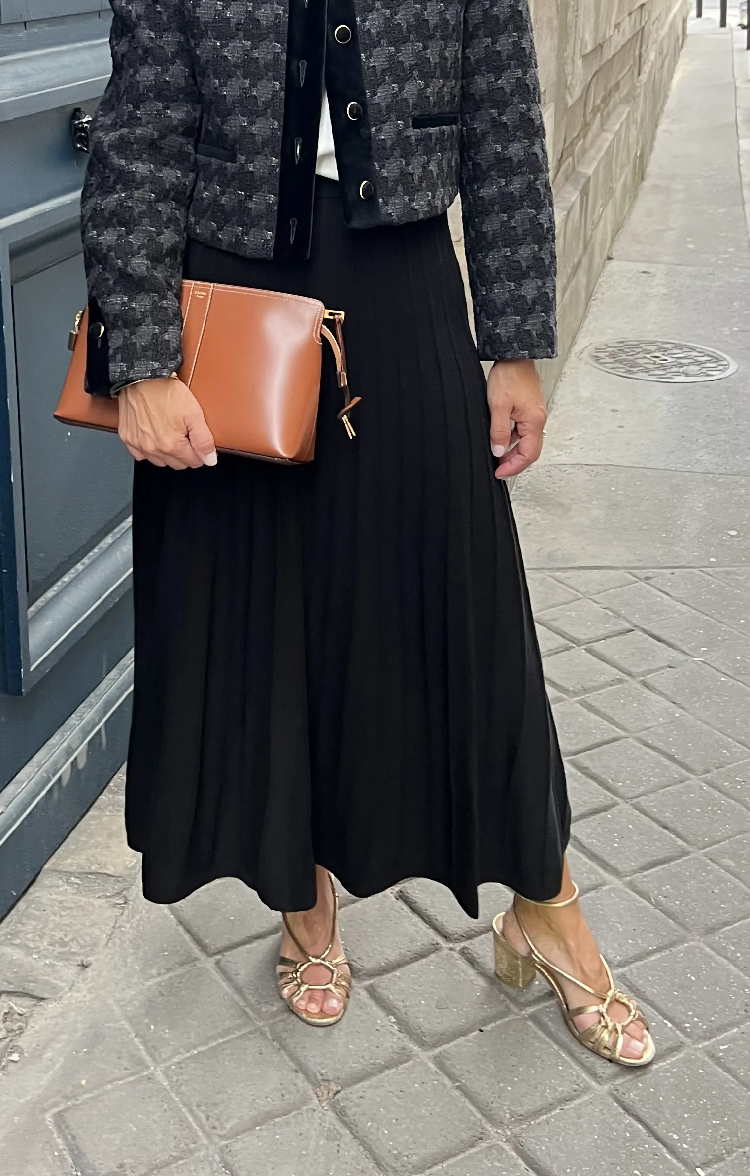 Woman wearing sezane gold sandals and a black skirt.