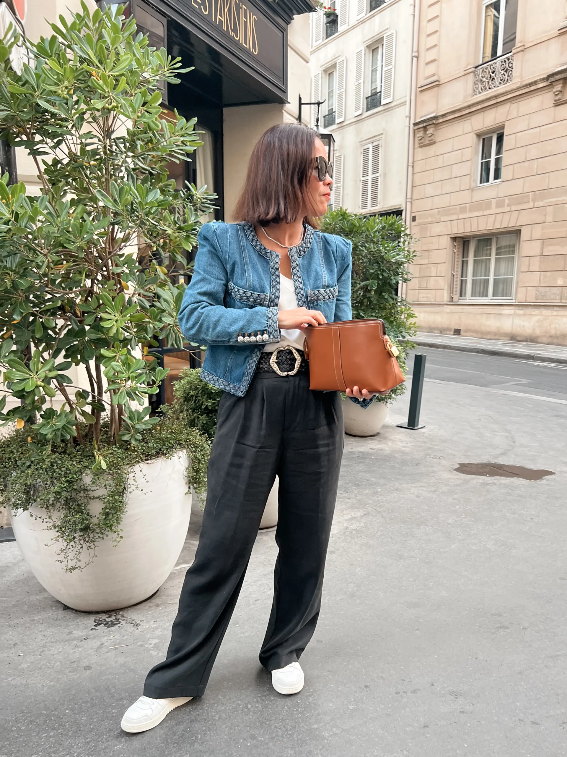 Woman wearing denim jacket with black silk pants standing on corner in Paris.