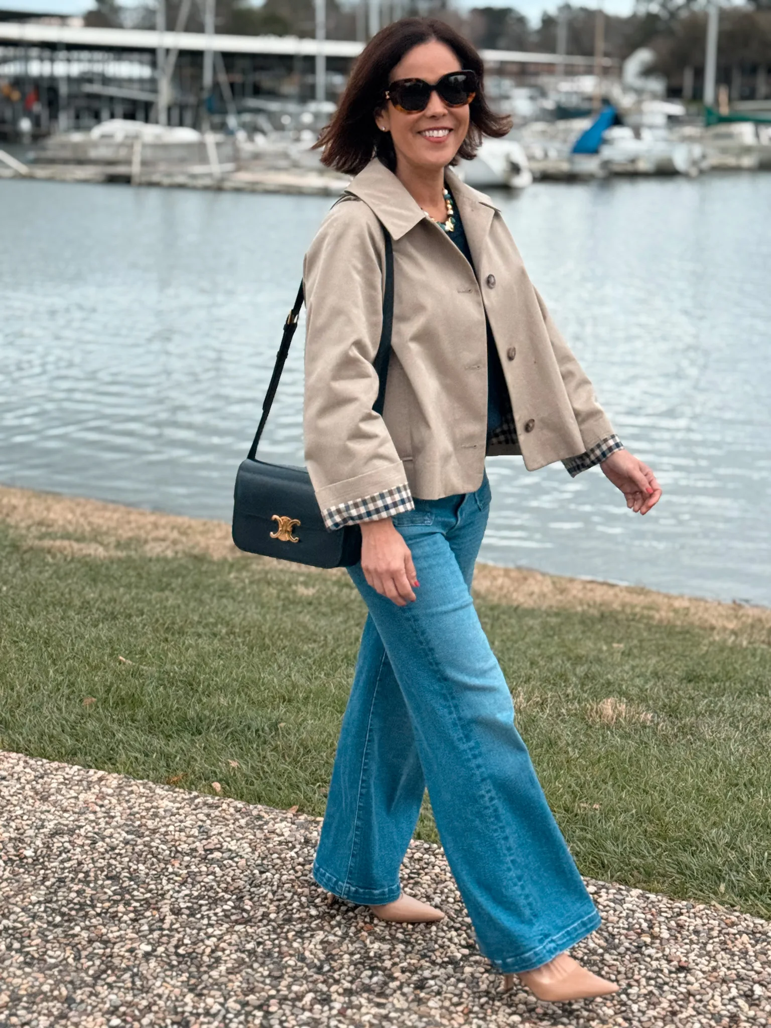 Lady walking with a trench coat, denim, and slingbacks.