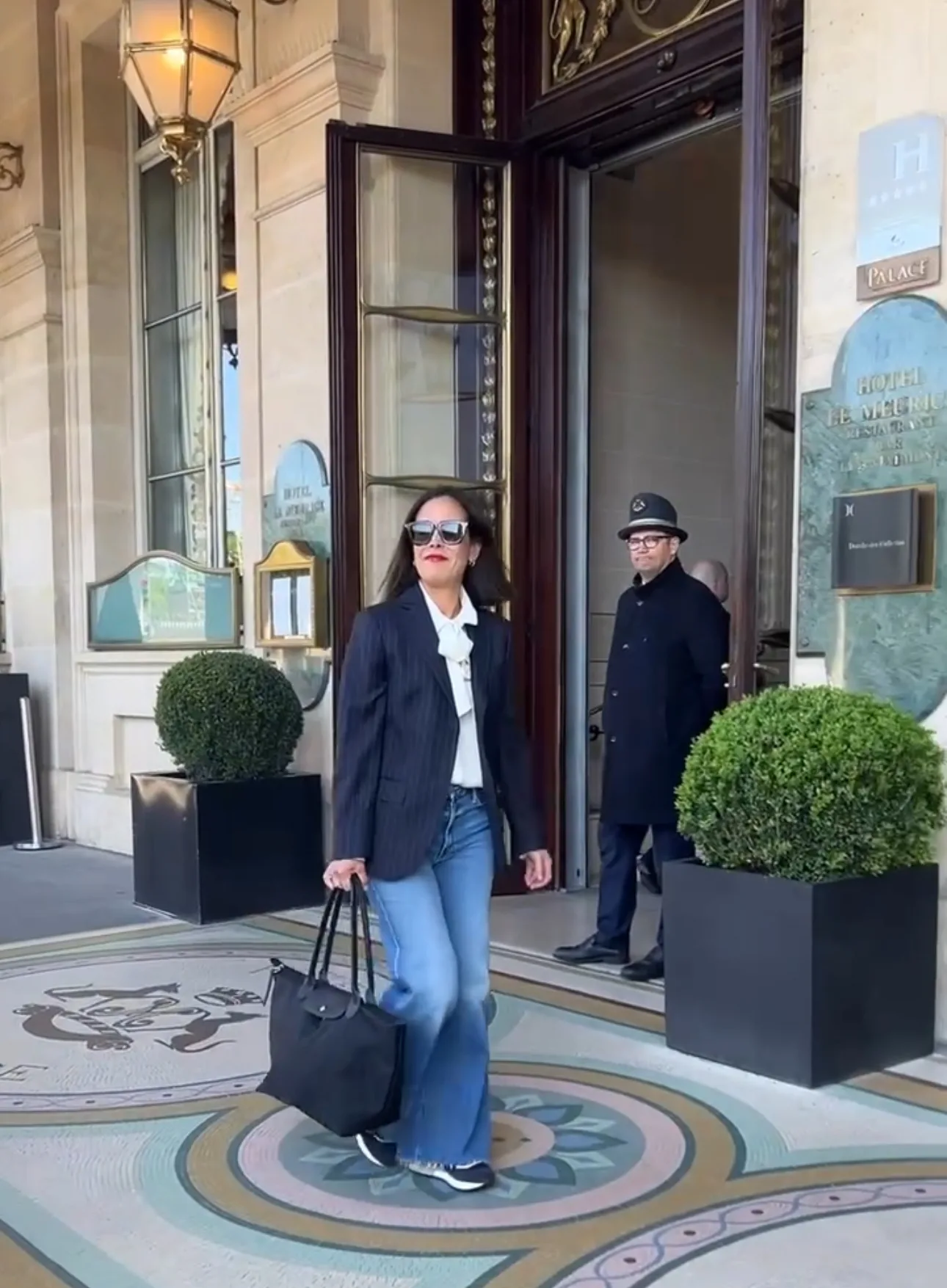 Woman wearing blazer and carrying longchamp bag.