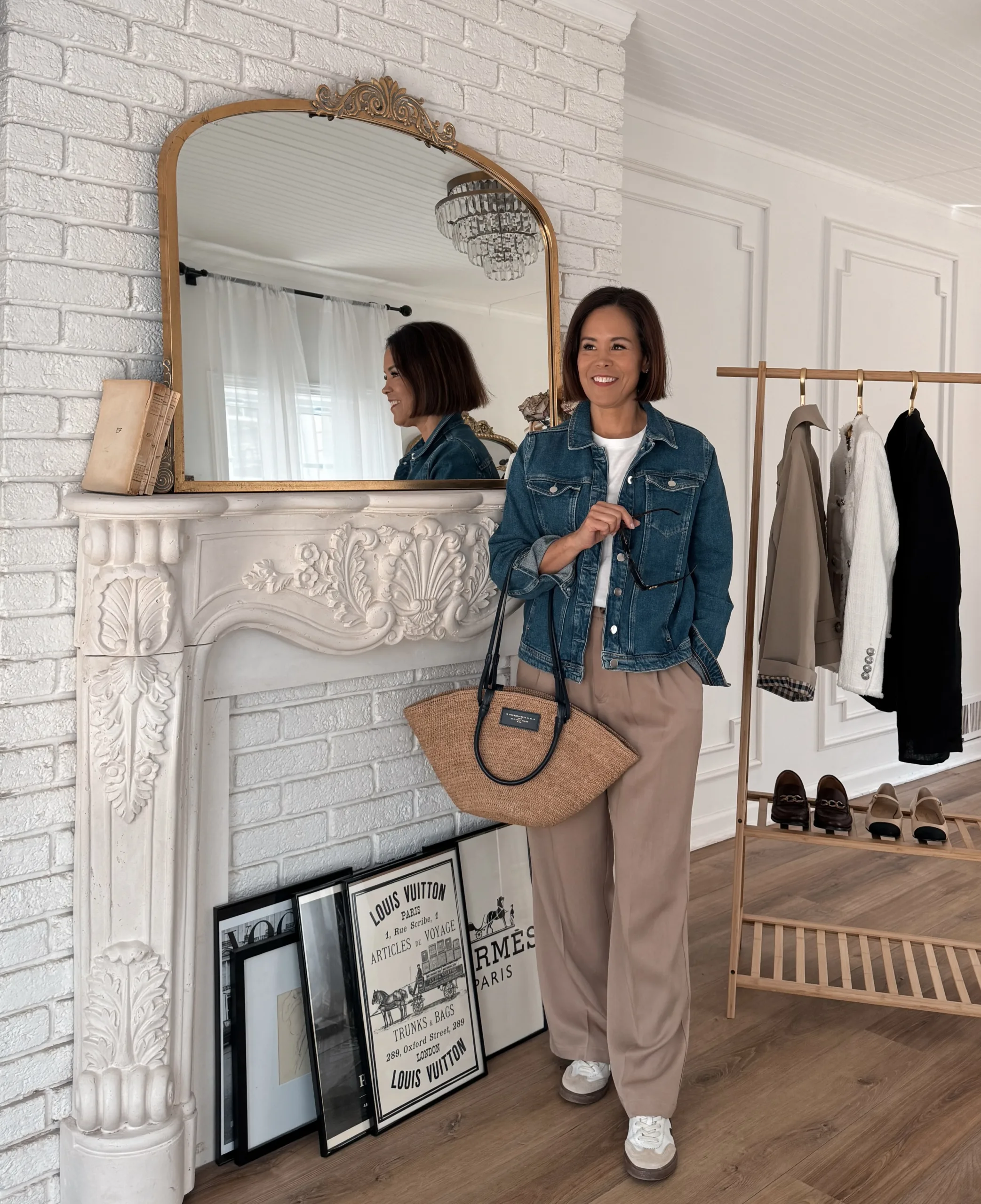 Woman wearing denim jacket with trousers and sneakers.