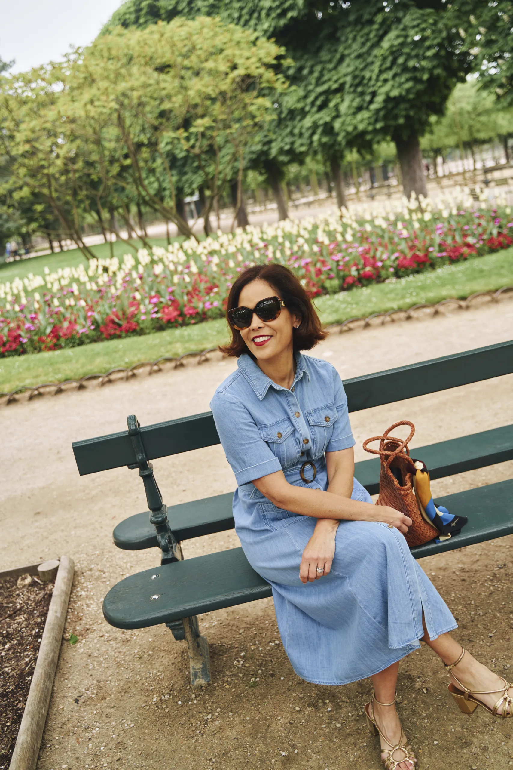 Woman wearing denim dress with gold sandals in Paris.