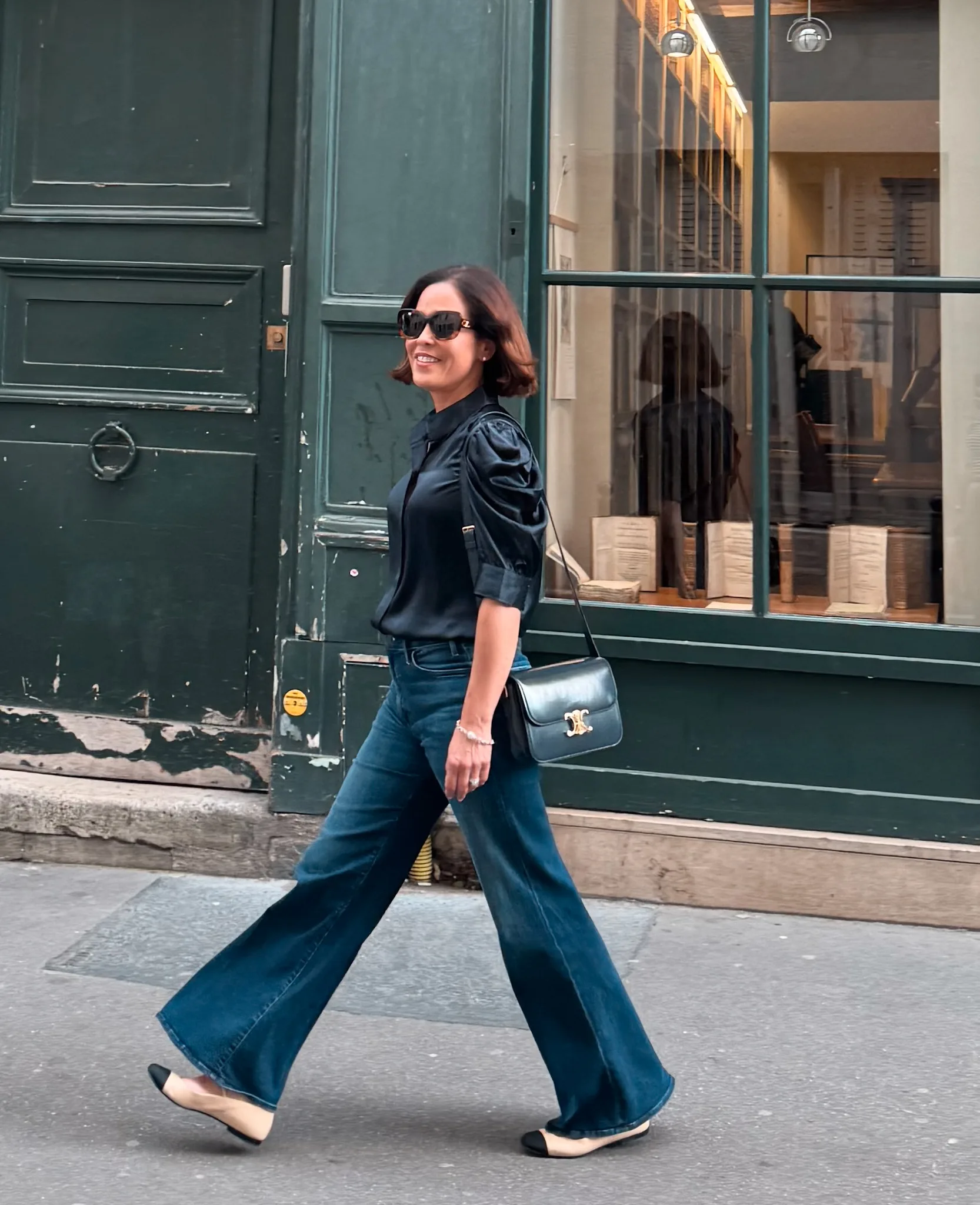 woman wearing navy silk top with wide leg denim and ballet flats.