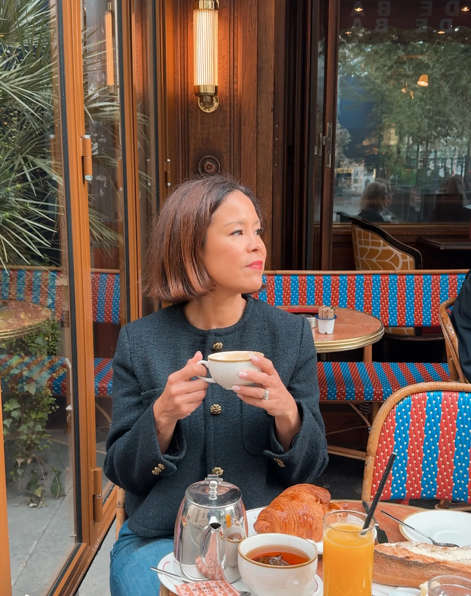 Woman wearing tweed jacket sipping coffee in Paris.