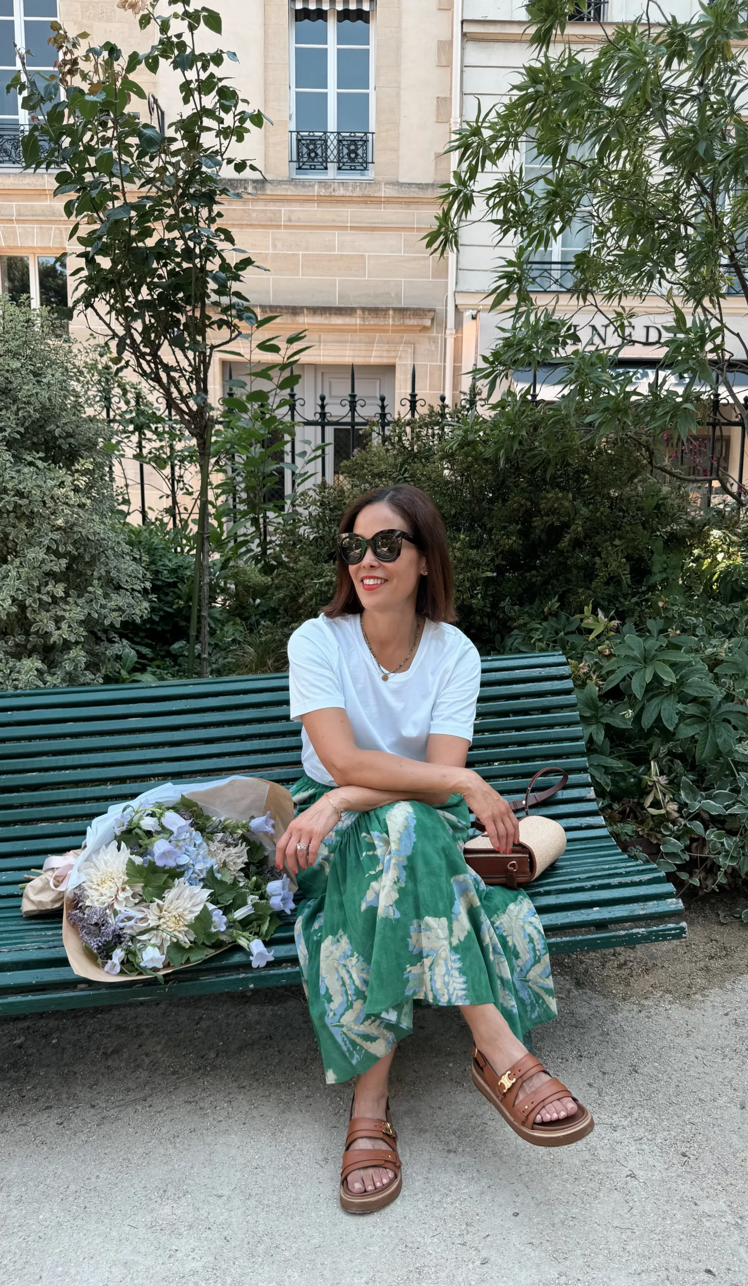 Woman with floral skirt, sandals, and white tee.