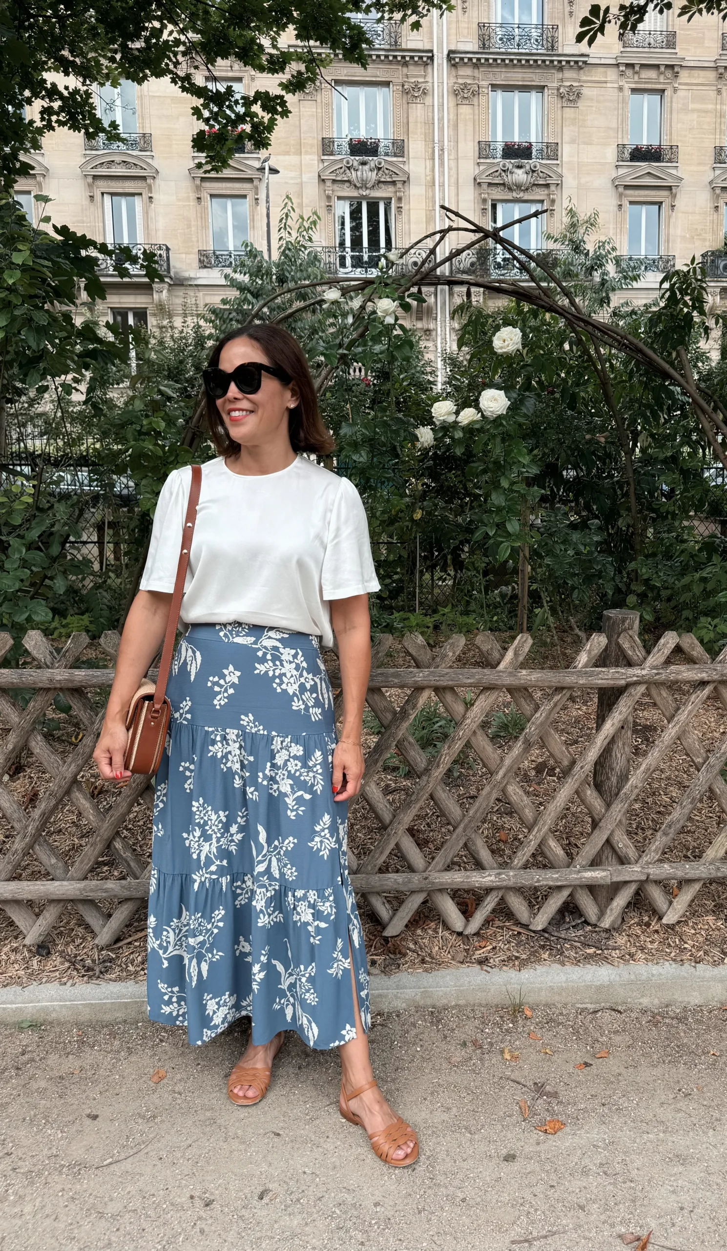 Woman in floral skirt with sillk top and sandals.