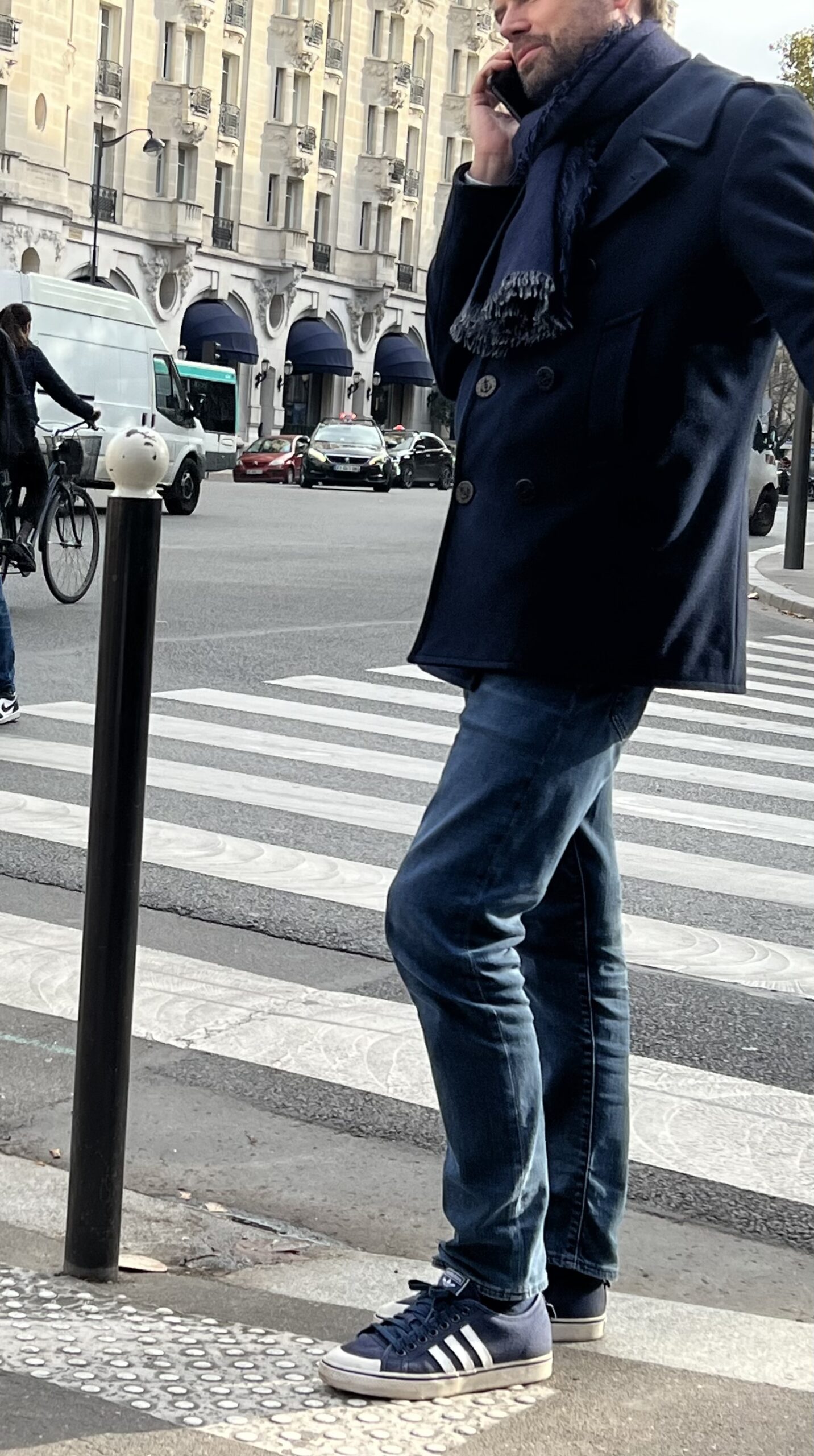 Man wearing navy coat with adidas and navy scarf in paris during the fall and autumn season.