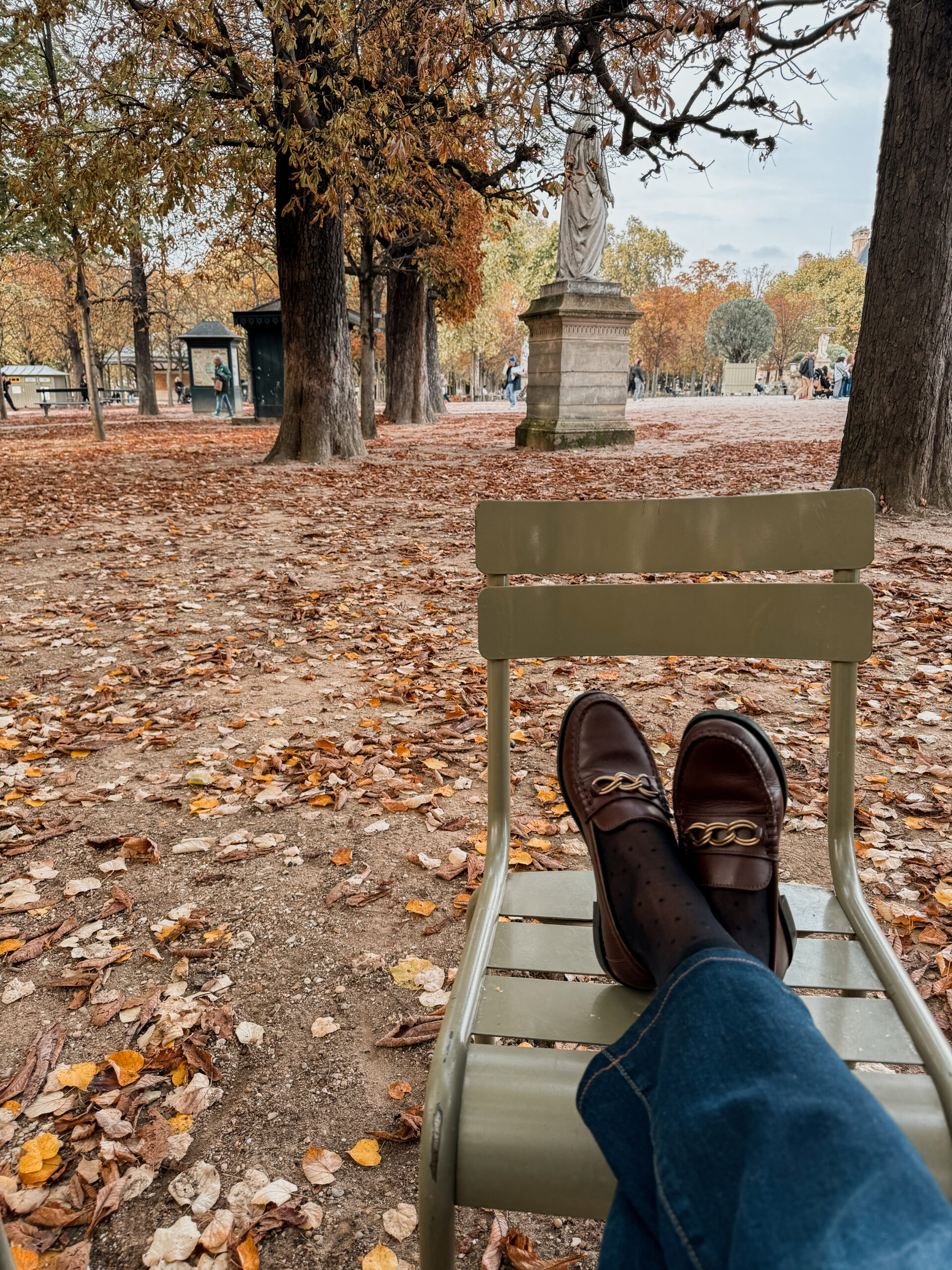 Woman with feet on chair in Paris in fall.