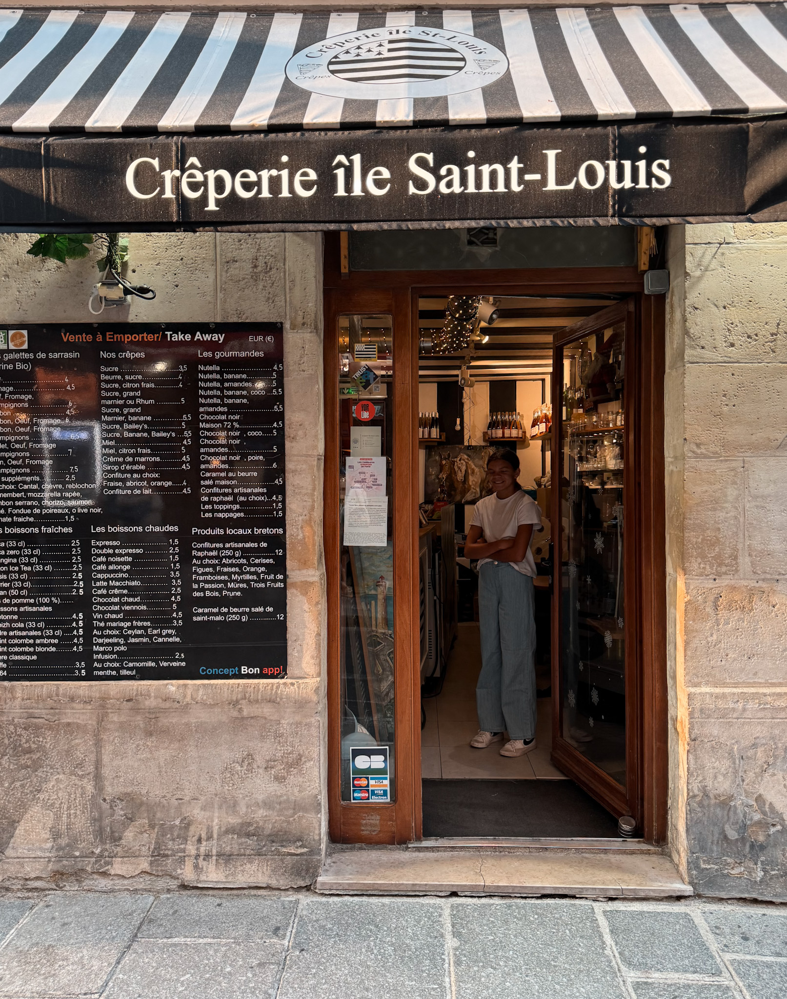 Little girl standing in doorway of a crepe place in Paris.