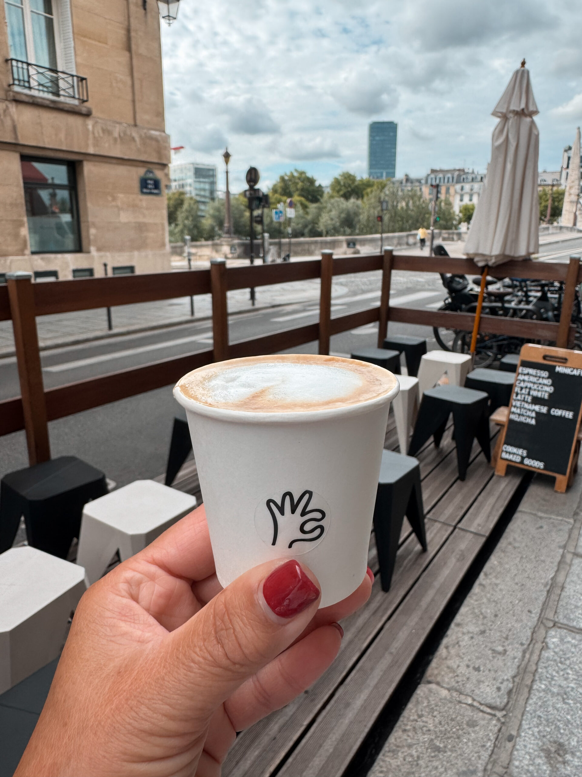 Person holding a tiny cup of coffee on ile saint louis.
