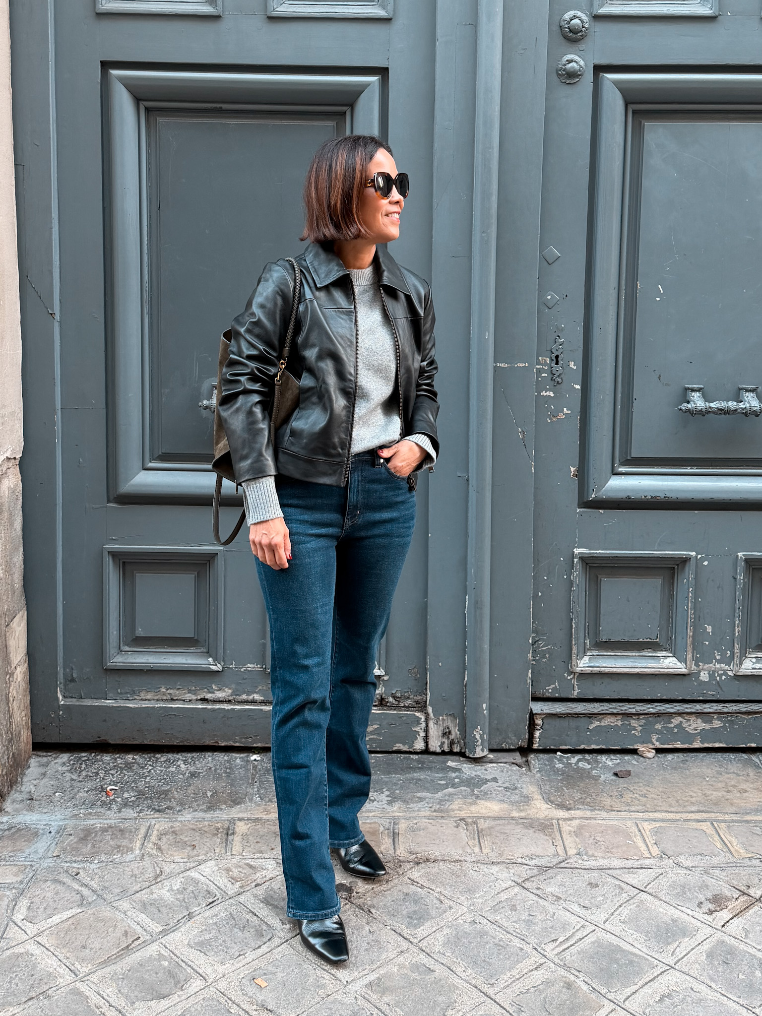 Woman wearing leather jacket and denim in Paris during fall.