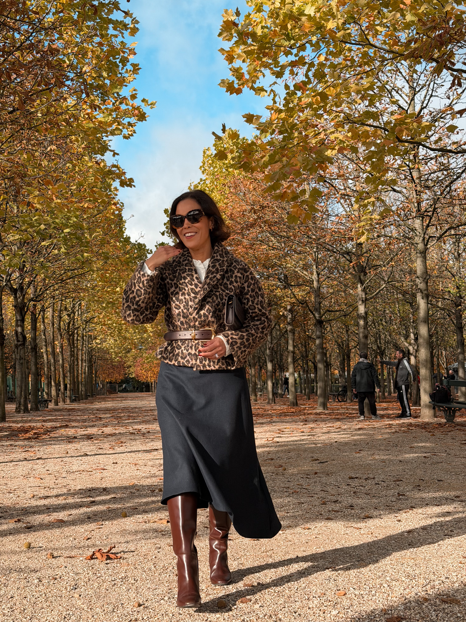 Woman wearing animal print jacket with wool skirt and tall boots walking through Luxemourg.