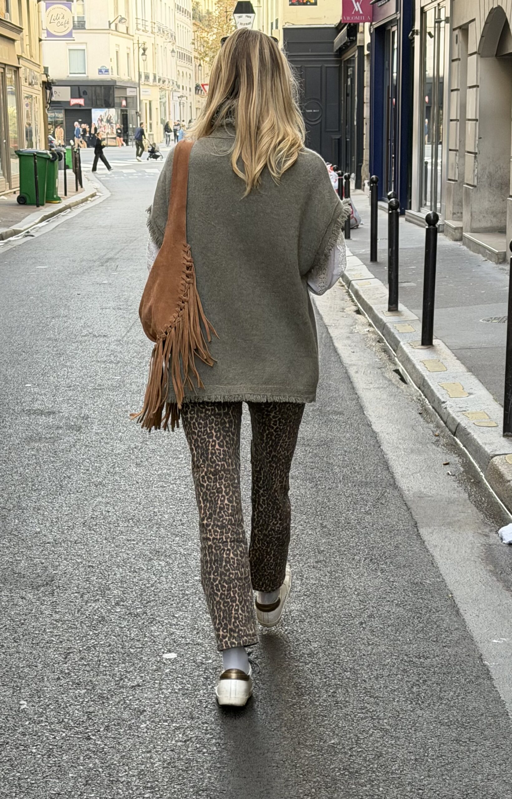 Woman walking down the street in paris wearing animal print pants and carrying suede bag.