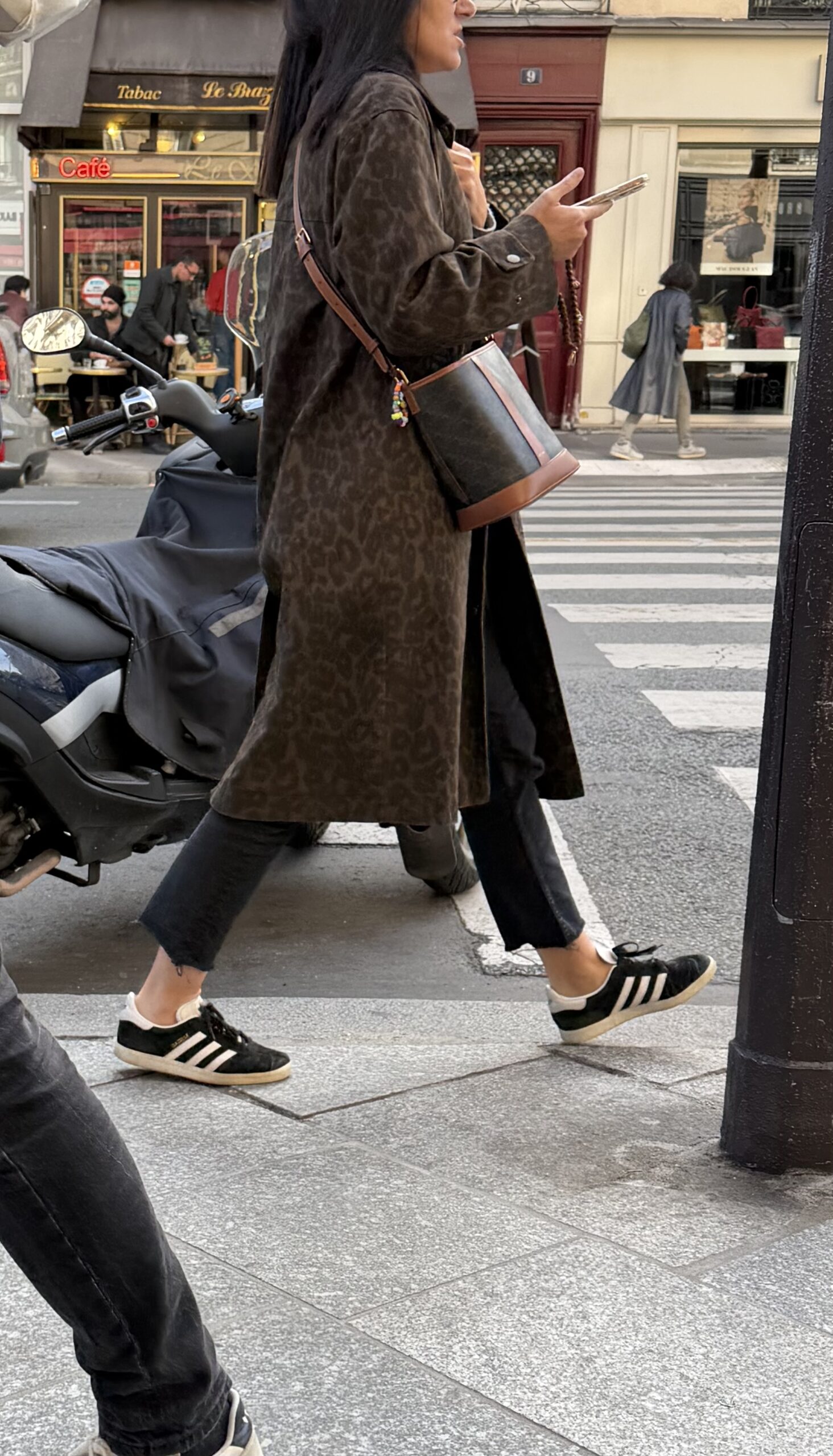 Woman in Paris during fall wearing animal print coat with black adidas sneakers.