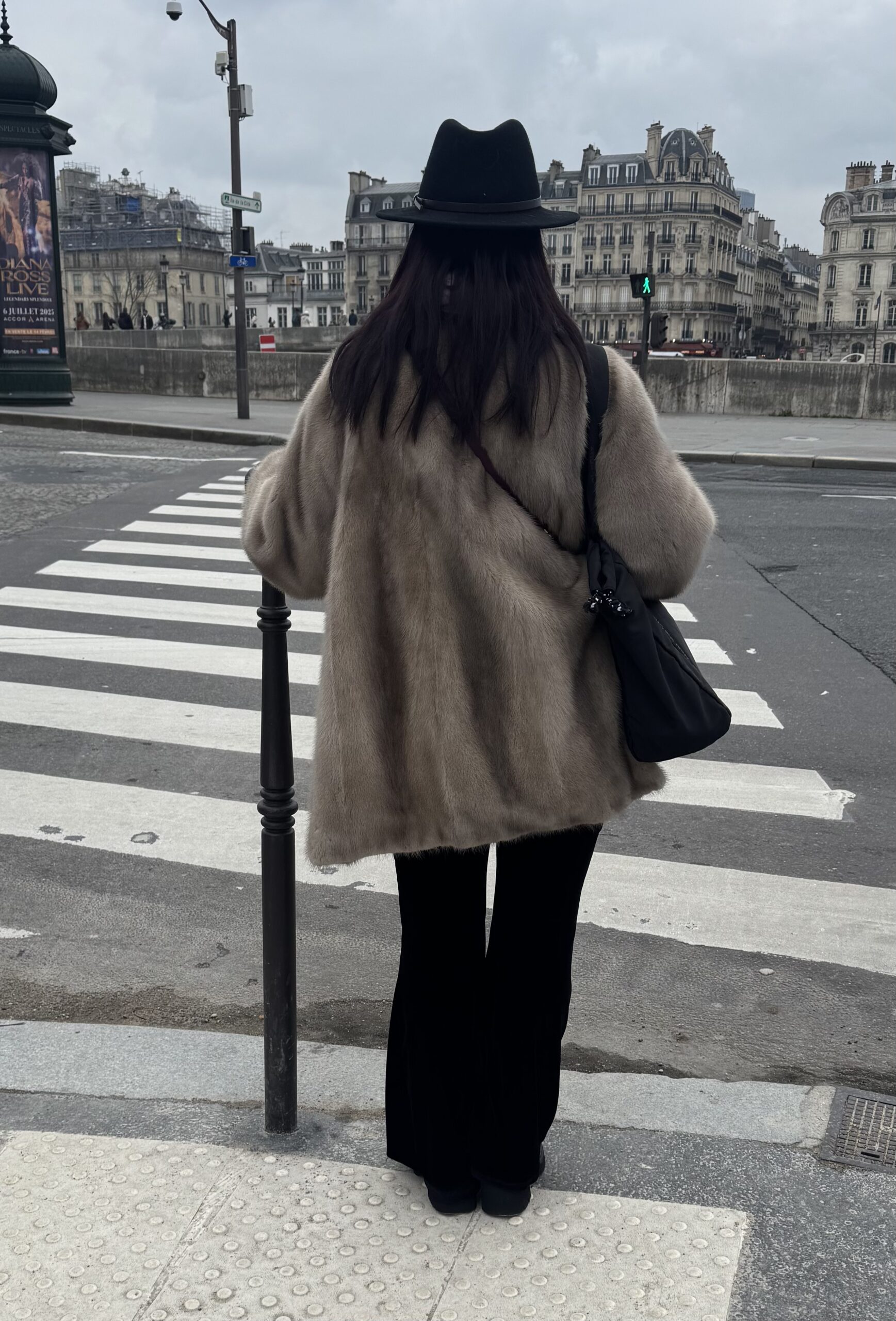 Woman walking with fur coat and hat in paris during January.