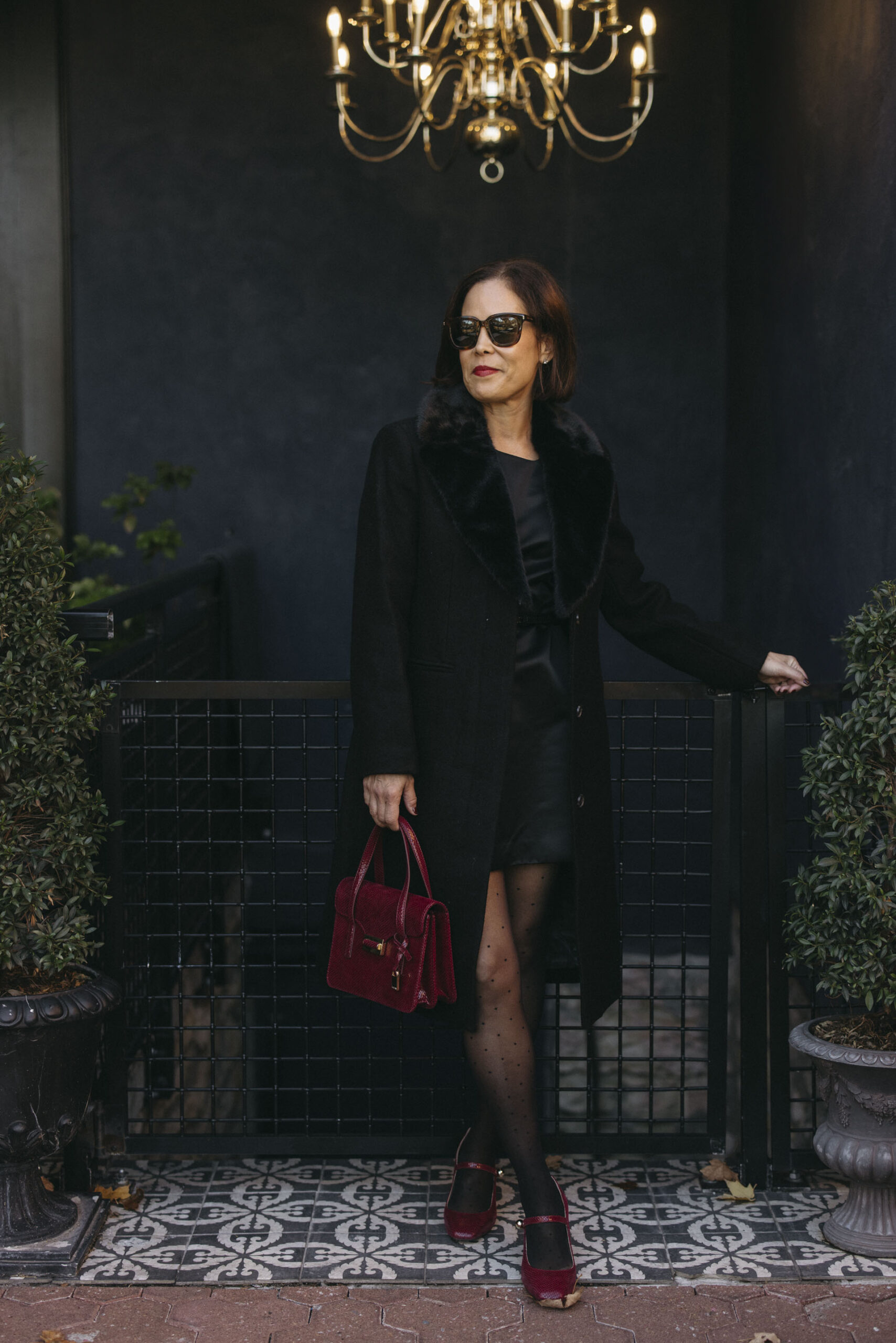 Woman wearing black dress with burgundy bag and heels.