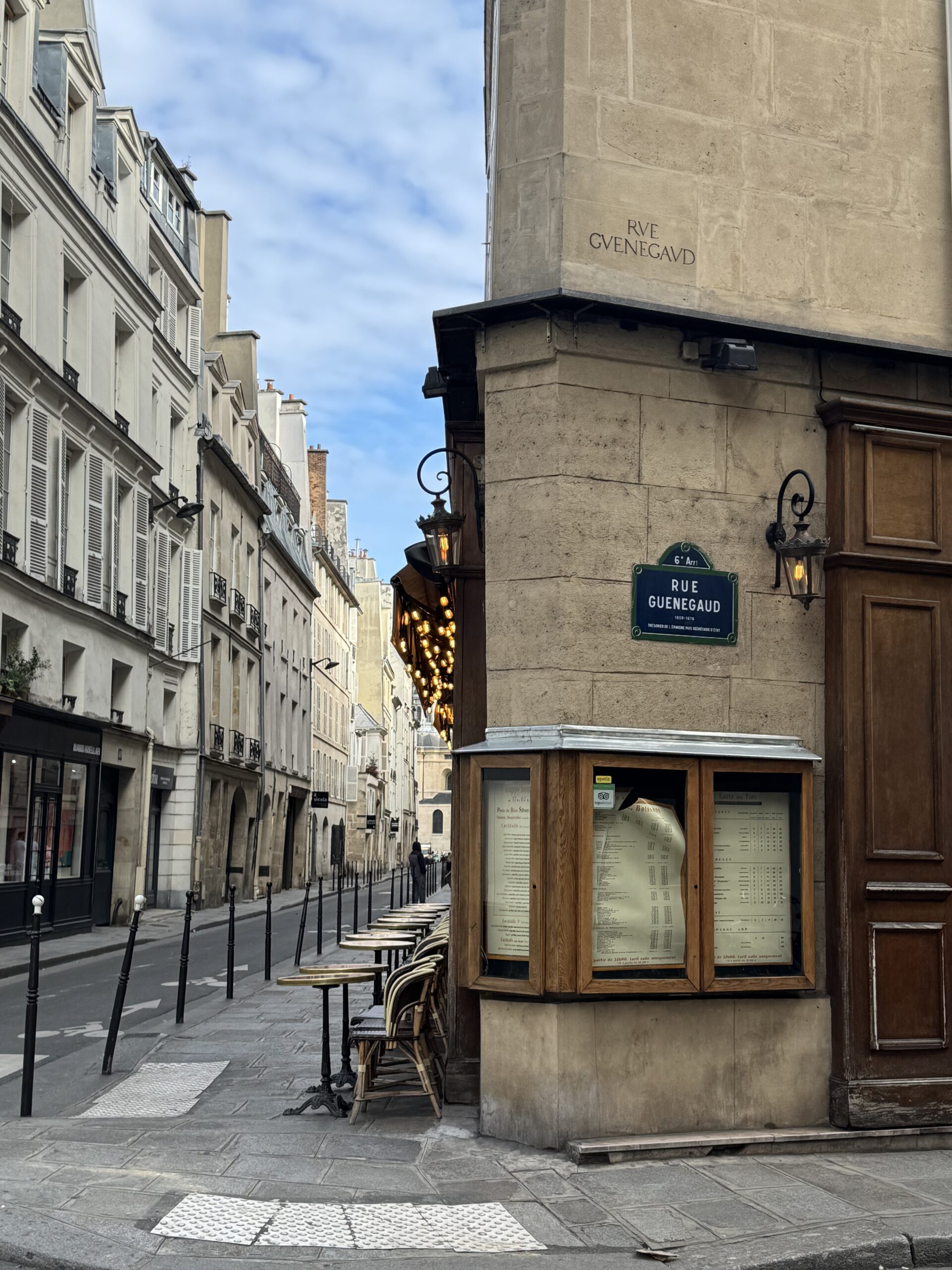 Photo of Parisian corner with street sign and restaurant on a corner.