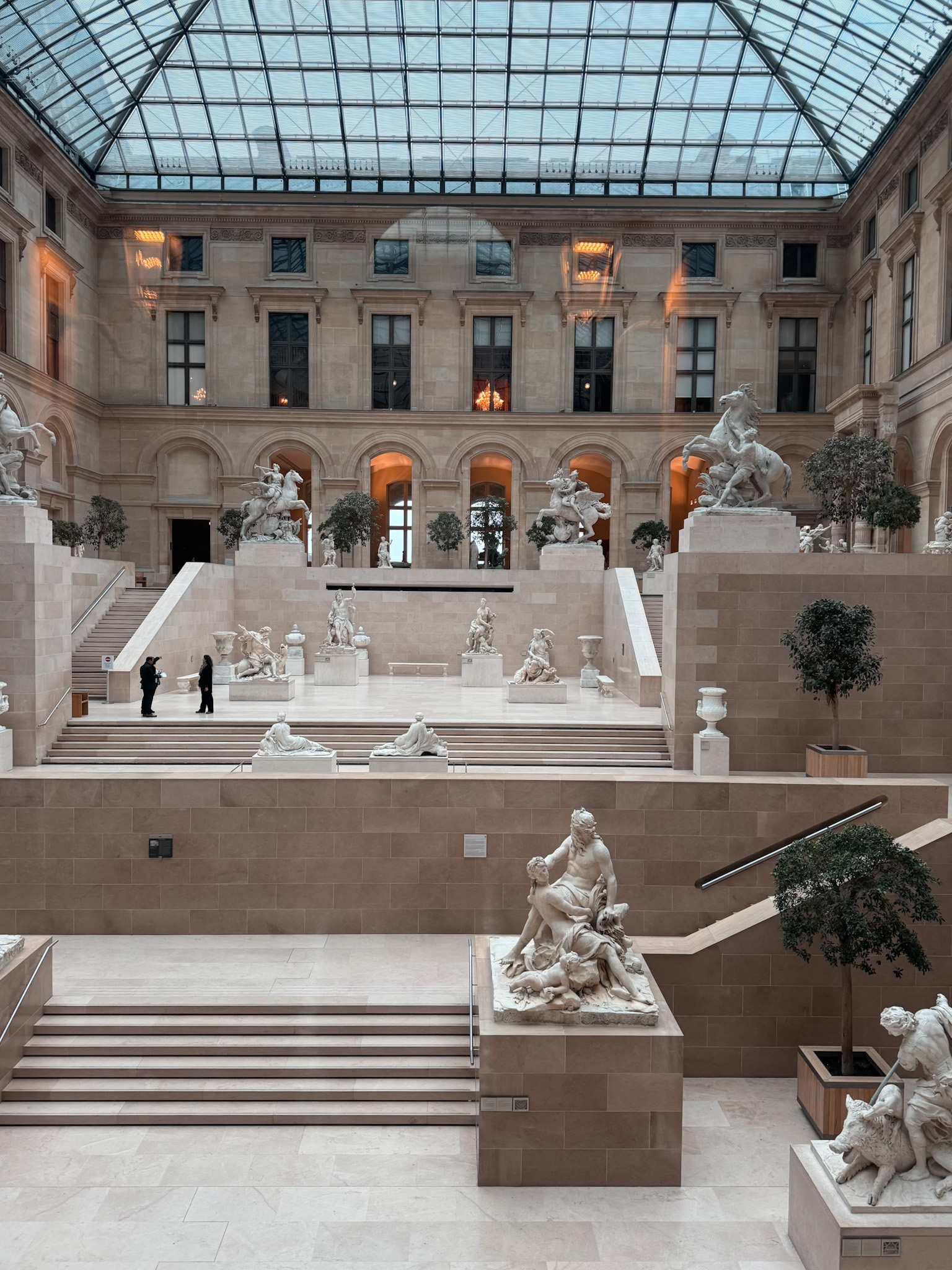Interior photo of the Louvre museum with white statues and staircases.