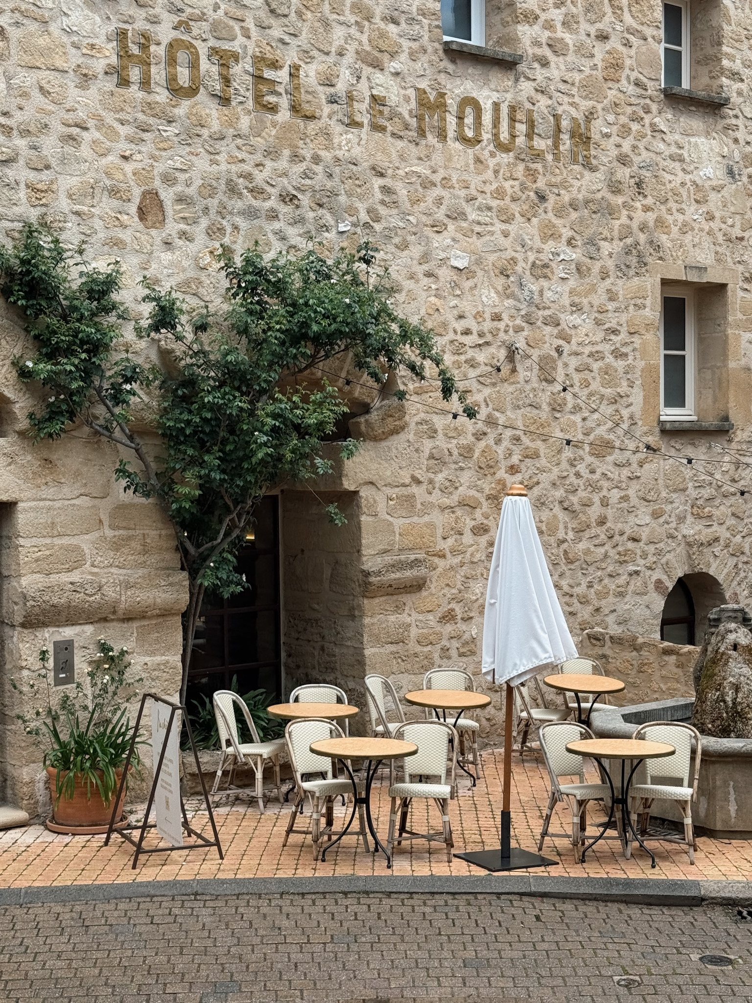 Courtyard café at Hotel Le Moulin Lourmarin with outdoor tables and stone walls in Provence