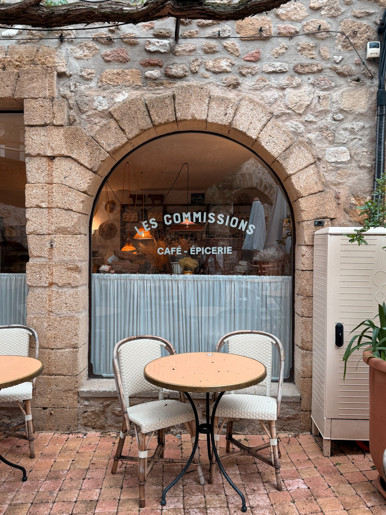 Les Commissions café-épicerie storefront with outdoor tables in Lourmarin village