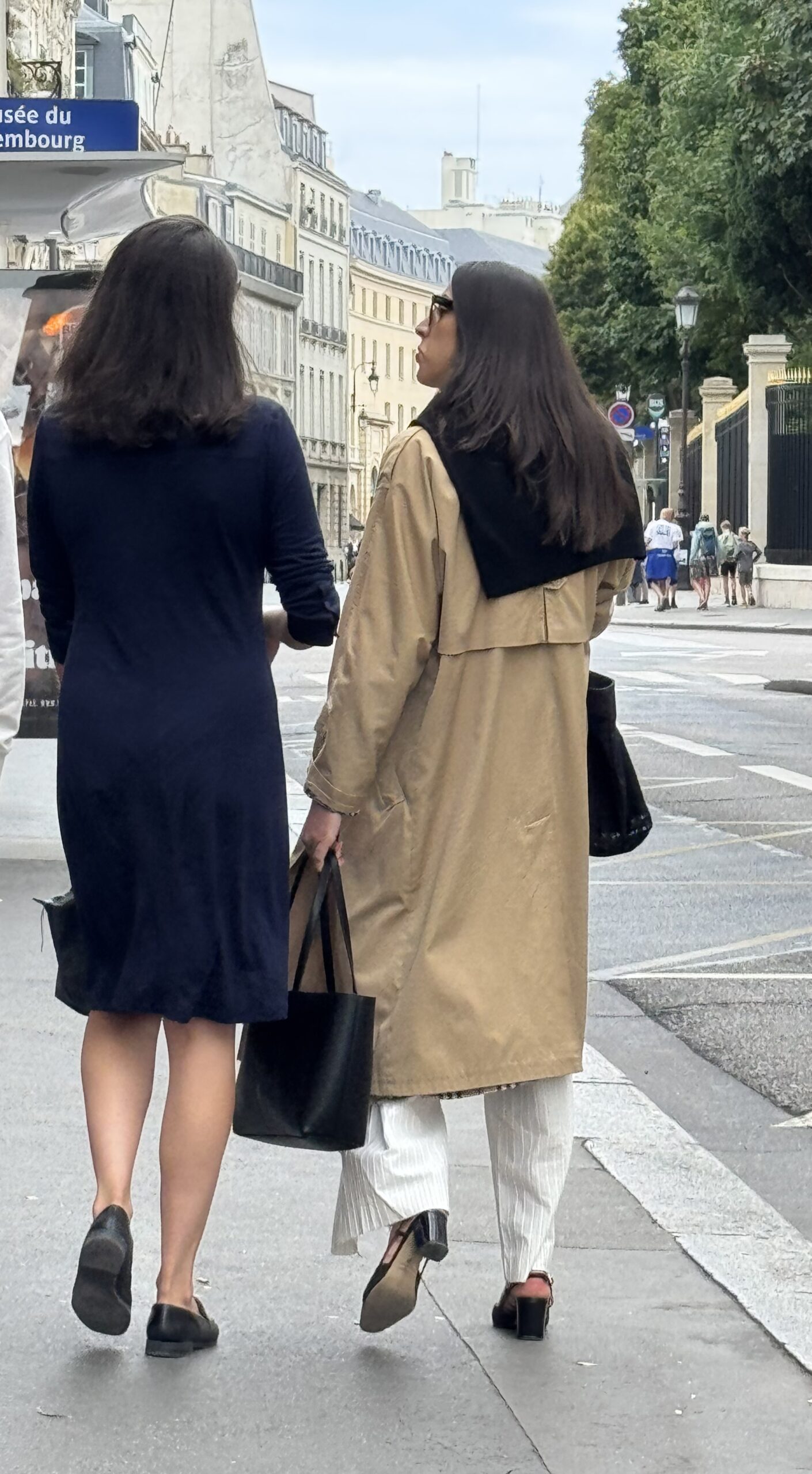 Parisian women wearing trench coats and neutral layers while walking in Paris